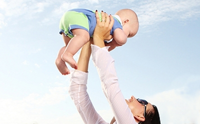 baby being held above mother looking down