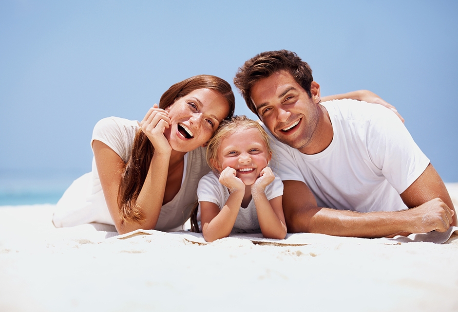 mother, child and father laying in sand